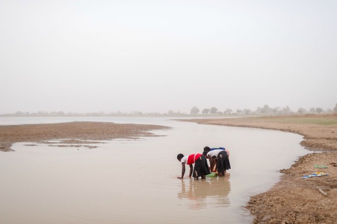 Các cô bé lấy nước bẩn từ một đập nước. Ảnh: WaterAid/ Nyani Quarmyne.